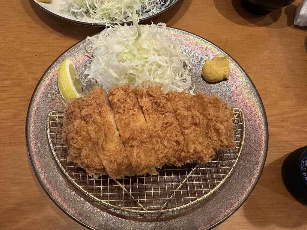 はせ川のひれかつ定食のかつ。網の上に切り分けたかつと、千切りキャベツ・レモン・からし
